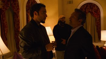 Movie still from “Full Circle” (2023), directed by Steven Soderbergh – Two men talking to each other in front of a lamp; Medium shot, Over the shoulder angle