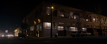 Movie still from “Stand Up Guys” (2012), directed by Fisher Stevens – A person walking down a street near a building at night; Extreme Wide shot, Low angle