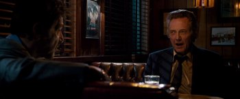 Movie still from “Stand Up Guys” (2012), directed by Fisher Stevens – A man sitting at a table in front of a window; Medium shot, Over the shoulder angle