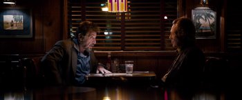 Movie still from “Stand Up Guys” (2012), directed by Fisher Stevens – A man sitting at a table in front of a woman; Medium shot, Over the shoulder angle