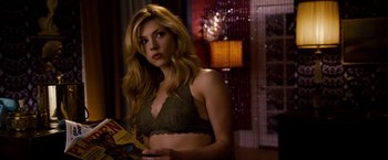 Movie still from “Stand Up Guys” (2012), directed by Fisher Stevens – A beautiful blonde woman in a green bra holding a magazine; Medium shot, Over the shoulder angle