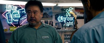 Movie still from “Stand Up Guys” (2012), directed by Fisher Stevens – A man standing in front of a corona light sign; Close Up shot, Over the shoulder angle