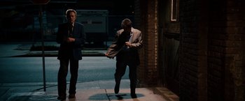 Movie still from “Stand Up Guys” (2012), directed by Fisher Stevens – A man in a suit and tie standing on a sidewalk; Wide shot, Low angle