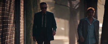 Movie still from “Stand Up Guys” (2012), directed by Fisher Stevens – A man wearing a suit and tie walking down a street; Medium shot, Low angle