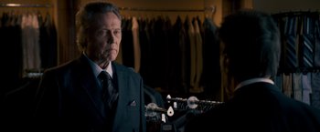 Movie still from “Stand Up Guys” (2012), directed by Fisher Stevens – An older man in a suit and tie in front of a row of suits; Medium shot, Over the shoulder angle