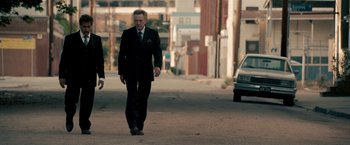Movie still from “Stand Up Guys” (2012), directed by Fisher Stevens – A man in a suit and tie walking down a street; Wide shot, Low angle