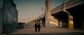 Movie still from “Stand Up Guys” (2012), directed by Fisher Stevens – Two men are walking down the street in front of a bridge; Extreme Wide shot, High angle