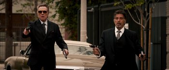 Movie still from “Stand Up Guys” (2012), directed by Fisher Stevens – Two men dressed in suits and holding guns in front of a car; Medium shot, Over the shoulder angle