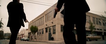 Movie still from “Stand Up Guys” (2012), directed by Fisher Stevens – A man holding a gun while walking down a street; Extreme Wide shot, Low angle