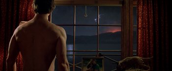 Movie still from “Starman” (1984), directed by John Carpenter – A man standing in front of a window at night; Medium shot, Over the shoulder angle