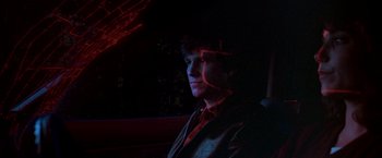 Movie still from “Starman” (1984), directed by John Carpenter – A man sitting in the back seat of a car at night; Close Up shot, Low angle