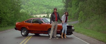 Movie still from “Starman” (1984), directed by John Carpenter – A man and a woman standing in front of a red car; Wide shot, Low angle