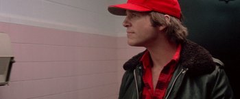 Movie still from “Starman” (1984), directed by John Carpenter – A man wearing a red hat and a red jacket; Close Up shot, Over the shoulder angle