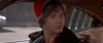 Movie still from “Starman” (1984), directed by John Carpenter – A person with a gun in a car; Close Up shot, Low angle