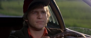 Movie still from “Starman” (1984), directed by John Carpenter – A person sitting in a car holding a steering wheel; Close Up shot, Over the shoulder angle