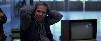 Movie still from “Starman” (1984), directed by John Carpenter – A man sitting on a chair with his hands behind his head; Close Up shot, Over the shoulder angle