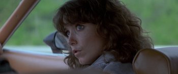 Movie still from “Starman” (1984), directed by John Carpenter – A person with long brown hair; Close Up shot, Over the shoulder angle