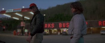 Movie still from “Starman” (1984), directed by John Carpenter – Two people standing in a parking lot at night; Medium shot, Over the shoulder angle