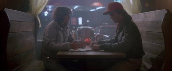 Movie still from “Starman” (1984), directed by John Carpenter – A man and a woman sitting at a table; Medium shot, Over the shoulder angle