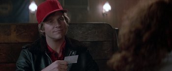 Movie still from “Starman” (1984), directed by John Carpenter – A man sitting in a chair holding a piece of paper; Close Up shot, Over the shoulder angle