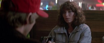 Movie still from “Starman” (1984), directed by John Carpenter – A woman sitting at a table in front of a man; Close Up shot, Over the shoulder angle