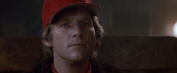 Movie still from “Starman” (1984), directed by John Carpenter – A person wearing a red hat; Close Up shot, Low angle