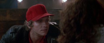 Movie still from “Starman” (1984), directed by John Carpenter – A man wearing a red hat talking to a woman; Close Up shot, Over the shoulder angle