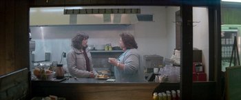Movie still from “Starman” (1984), directed by John Carpenter – Two women are talking in a restaurant kitchen; Medium shot, Over the shoulder angle