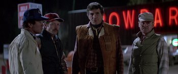 Movie still from “Starman” (1984), directed by John Carpenter – A man in a vest and a hat standing next to a man in a hat; Medium shot, Low angle