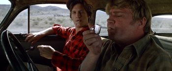 Movie still from “Starman” (1984), directed by John Carpenter – Two men sitting in the back seat of a car; Medium shot, Low angle