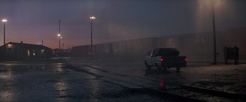 Movie still from “Starman” (1984), directed by John Carpenter – A car driving down a street in the rain; Extreme Wide shot, Low angle
