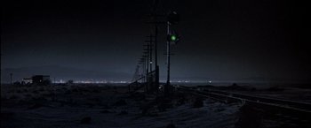 Movie still from “Starman” (1984), directed by John Carpenter – A green light on a pole in the middle of a field at night; Extreme Wide shot, Low angle