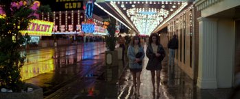 Movie still from “Starman” (1984), directed by John Carpenter – Two women walking down the street in the rain at night; Wide shot, Low angle