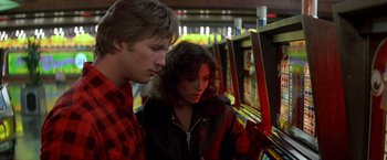 Movie still from “Starman” (1984), directed by John Carpenter – A man and a woman are looking at a video game; Close Up shot, Over the shoulder angle
