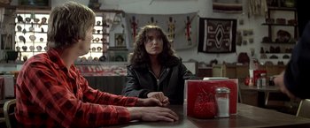 Movie still from “Starman” (1984), directed by John Carpenter – A woman sitting at a table with another woman; Medium shot, Over the shoulder angle
