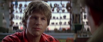 Movie still from “Starman” (1984), directed by John Carpenter – A man in a red and black plaid shirt looking at the camera; Close Up shot, Over the shoulder angle