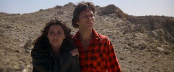 Movie still from “Starman” (1984), directed by John Carpenter – A man and a woman standing next to each other on top of a hill; Medium shot, Low angle