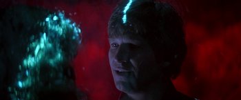 Movie still from “Starman” (1984), directed by John Carpenter – A young man with blue light shining on his face; Close Up shot, Over the shoulder angle