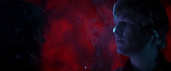 Movie still from “Starman” (1984), directed by John Carpenter – A man is looking into the distance in front of a red background; Close Up shot, Low angle