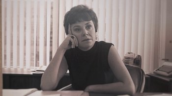 Movie still from “Street Gang: How We Got to Sesame Street” (2021), directed by Marilyn Agrelo – A woman sitting at a desk with her hand on her head; Close Up shot, Low angle