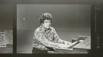 Movie still from “Street Gang: How We Got to Sesame Street” (2021), directed by Marilyn Agrelo – A black and white photo of a man sitting at a piano; Medium shot, Low angle
