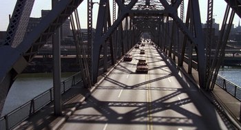 Movie still from “Stripes” (1981), directed by Ivan Reitman – Cars are driving on a bridge over a river; Extreme Wide shot, High angle