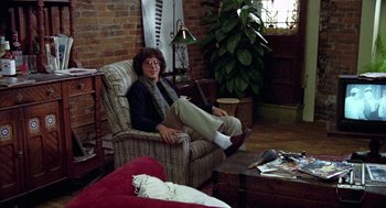 Movie still from “Stripes” (1981), directed by Ivan Reitman – A man sitting in a chair in a living room; Wide shot, High angle
