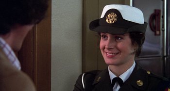 Movie still from “Stripes” (1981), directed by Ivan Reitman – A woman in a uniform smiles for the camera; Close Up shot, Over the shoulder angle