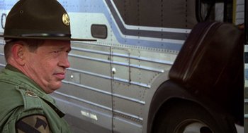 Movie still from “Stripes” (1981), directed by Ivan Reitman – A man in a military uniform standing next to a truck; Close Up shot, Over the shoulder angle