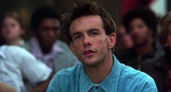 Movie still from “Stripes” (1981), directed by Ivan Reitman – A man with spiky brown hair wearing a blue shirt; Close Up shot, Over the shoulder angle