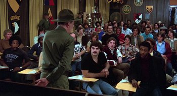 Movie still from “Stripes” (1981), directed by Ivan Reitman – A group of people sitting in a room; Medium shot, Over the shoulder angle