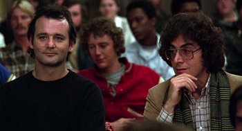 Movie still from “Stripes” (1981), directed by Ivan Reitman – A group of people sitting in front of a crowd; Close Up shot, Low angle