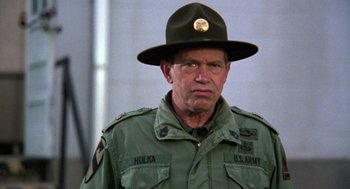 Movie still from “Stripes” (1981), directed by Ivan Reitman – An older man wearing a hat and a uniform; Close Up shot, Over the shoulder angle