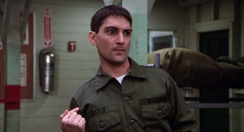 Movie still from “Stripes” (1981), directed by Ivan Reitman – A man in a green shirt is standing in front of a wall; Close Up shot, Low angle